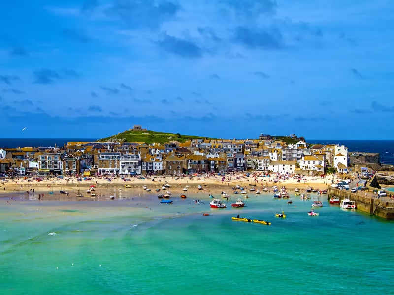 Strand met boten en dorp aan zee in Engeland.