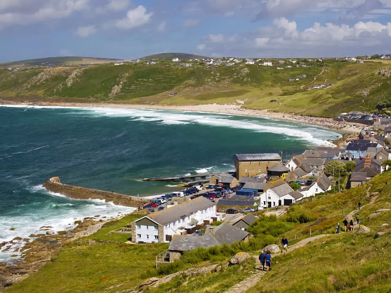 Kustplaats met heuvels en blauwe zee in Cornwall.
