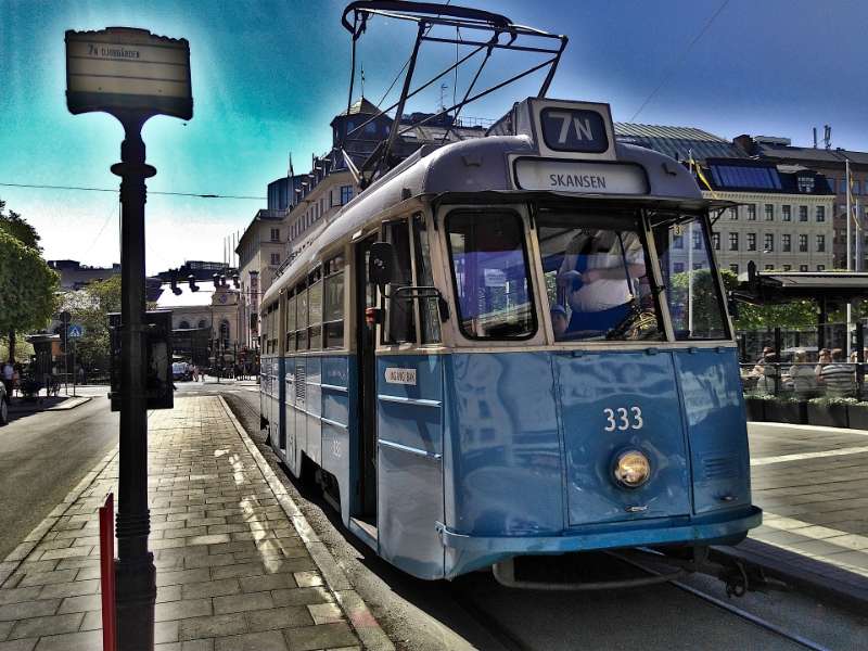 Blauwe tram in stadsverkeer met passagiers