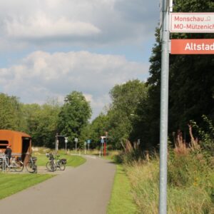 Fietspad met richtingborden en mensen bij schuilhut
