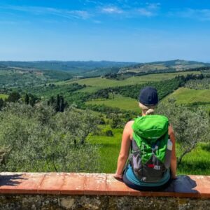 Persoon geniet van groen heuvellandschap onder blauwe lucht.