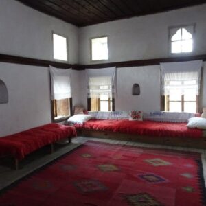 Traditionele kamer met rode tapijten en houten zitbanken.