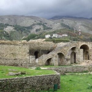 Oude stenen ruïnes met bergen op de achtergrond.