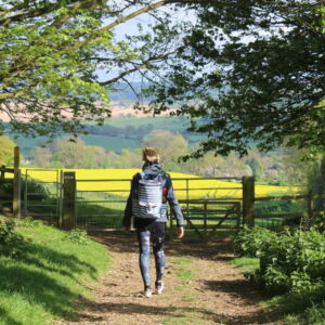 Wandelaar in zonnige landelijke omgeving met bloemenvelden.