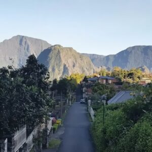 Bergdorp met weelderige bossen en bergen op achtergrond.