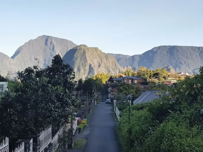 Bergdorp met weelderige bossen en bergen op achtergrond.
