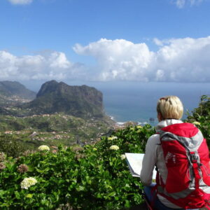 Wandelaar geniet van heuvelachtig uitzicht op zee.
