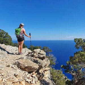 Vrouw wandelt op rotsachtig pad met zeezicht.
