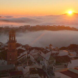 Zonsopgang boven een stad met mistige heuvels.