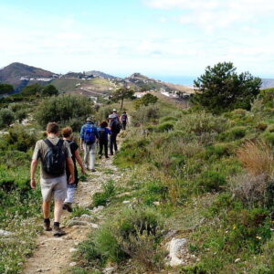 Groep wandelaars op bergpad met uitzicht.