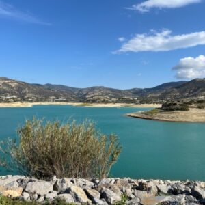 Blauw meer omgeven door bergen onder wolkenlucht.