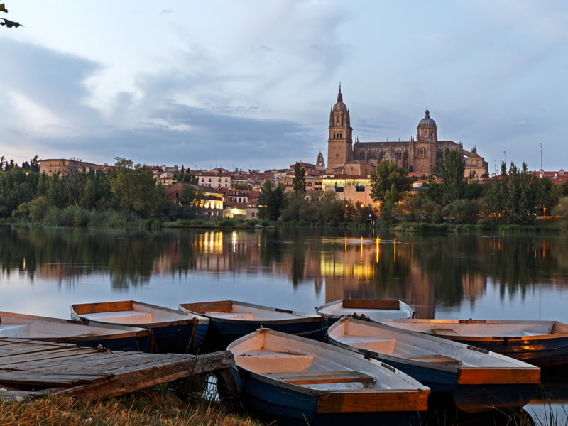 Kerk en boten bij zonsondergang aan rivier in Spanje.
