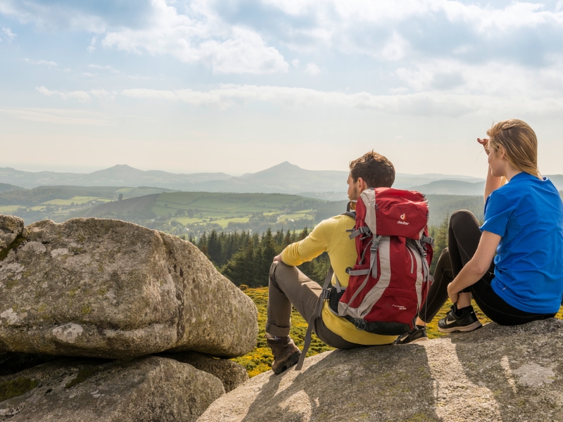 Twee wandelaars genieten van berglandschap op rotsen.