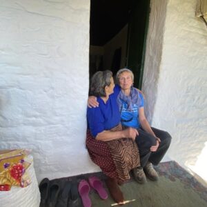 Twee vrouwen zittend in deuropening van stenen huis.