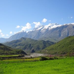 Bergen met sneeuw en groene vallei in zonlicht.