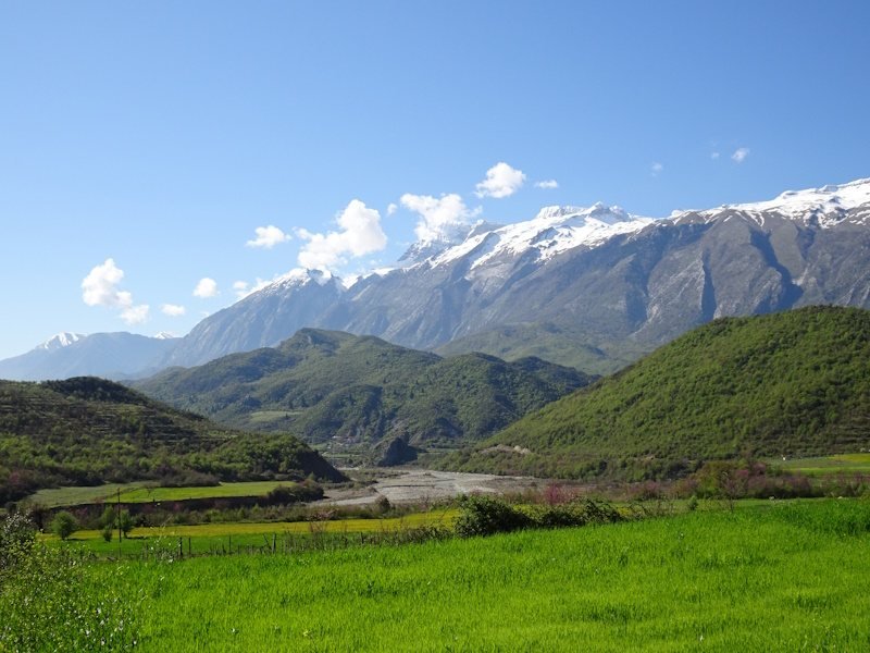 Bergen met sneeuw en groene vallei in zonlicht.