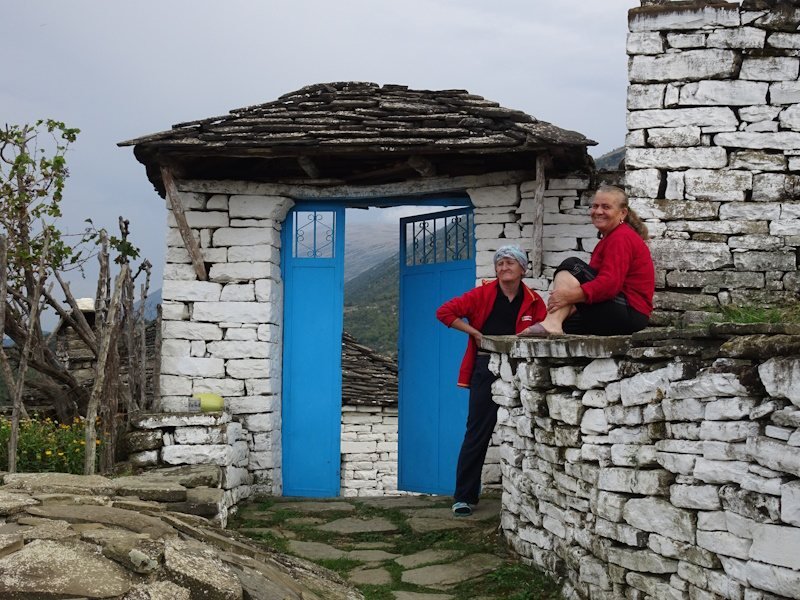 Twee mensen bij stenen poort met blauwe deuren.